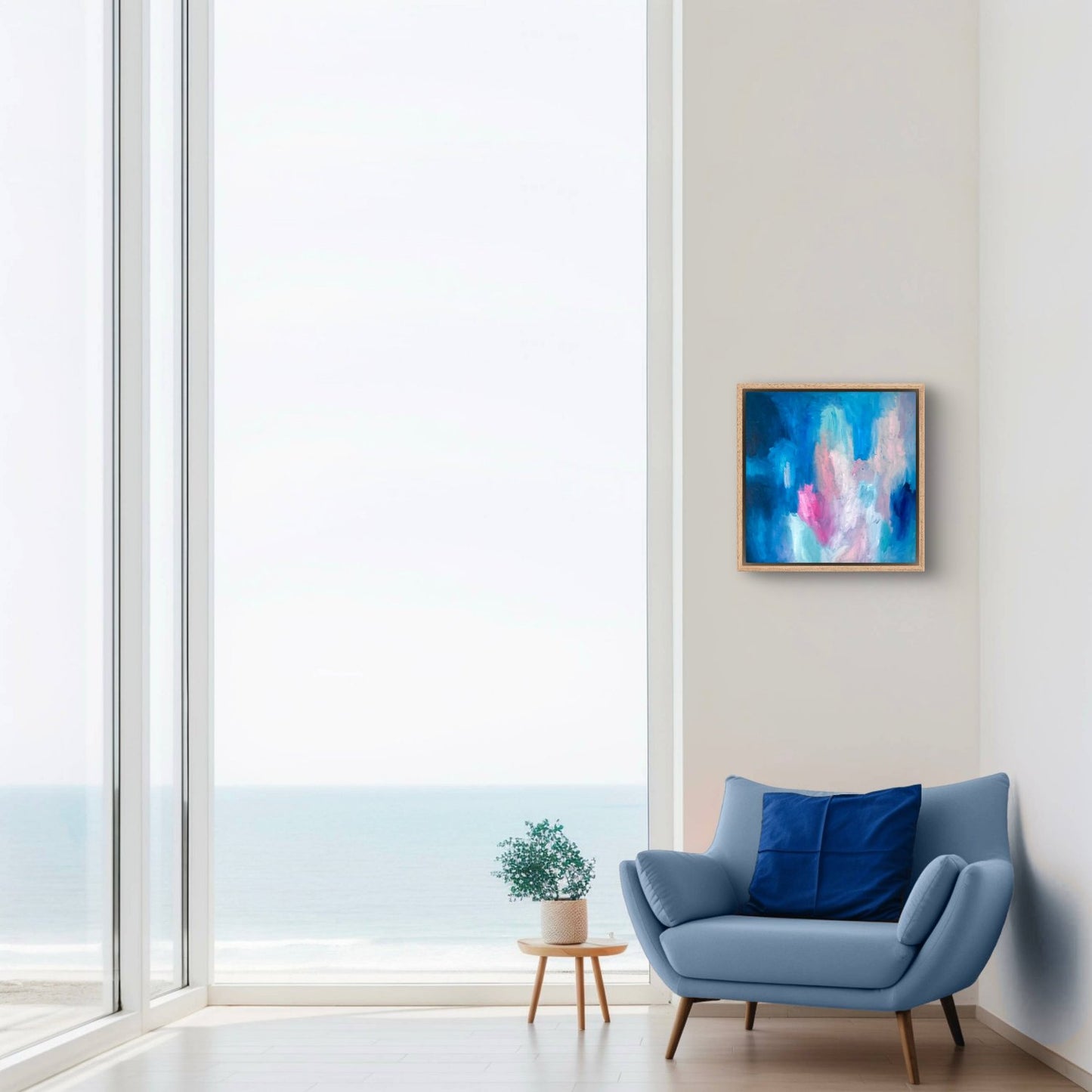 dark blue, peach and pink oil abstract painting in an oak frame hanging next to a big window and blue armchair