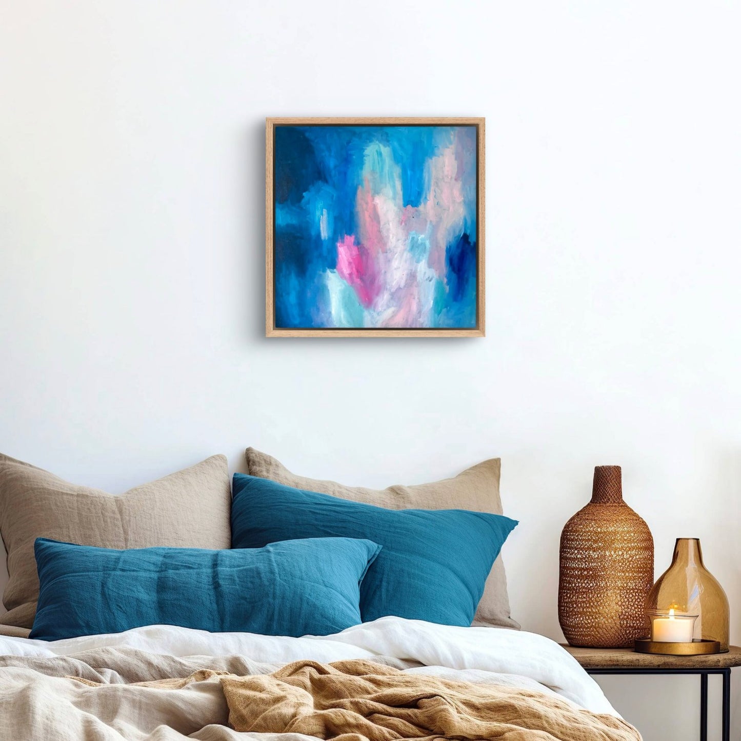 dark blue, peach and pink oil abstract painting in an oak frame, hanging above a bed with teal cushions