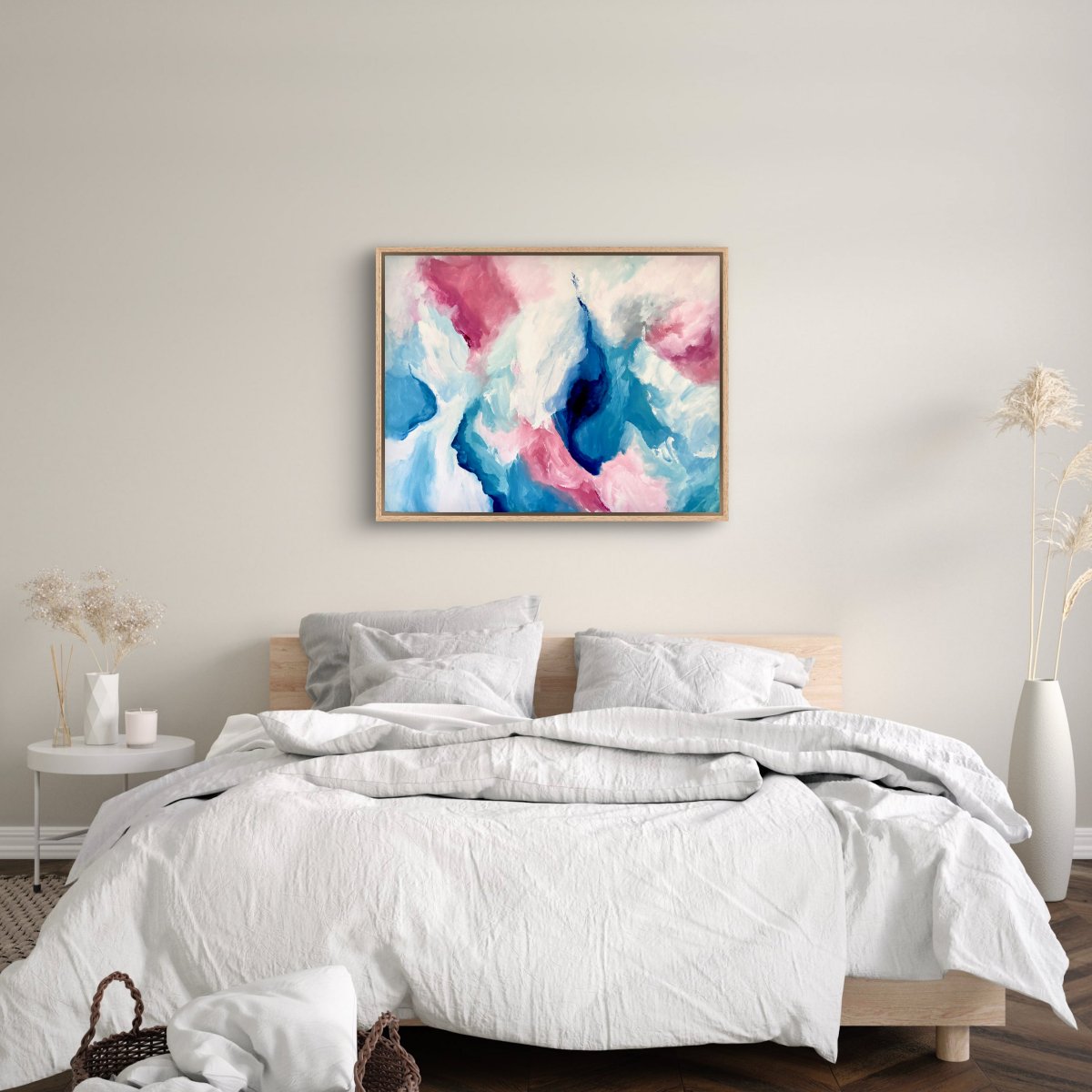 Framed original painting of abstract clouds in blue, green, peach and white hanging in a bedroom with a white quilted bed