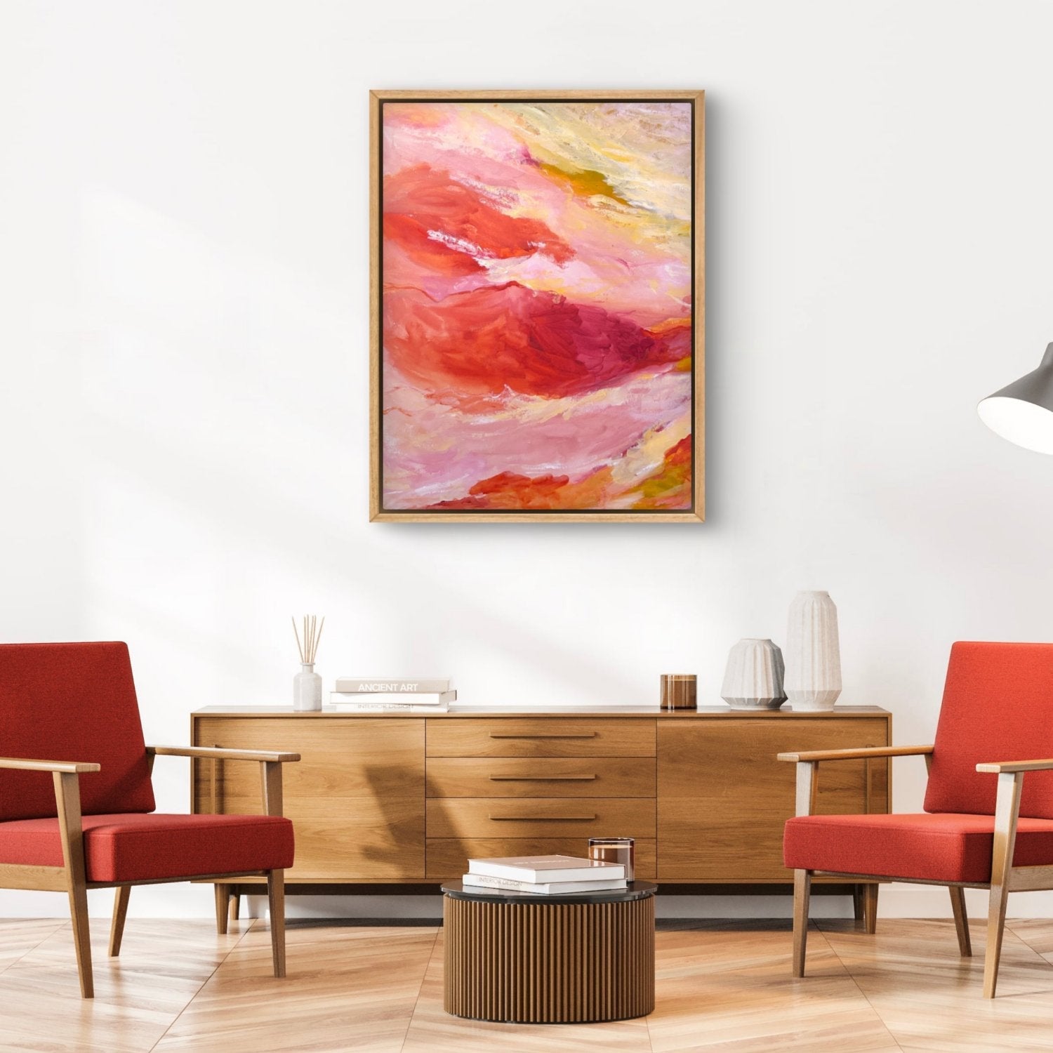 large abstract landscape painting with orange, pink and yellow colours, hanging in a loungeroom with orange chairs