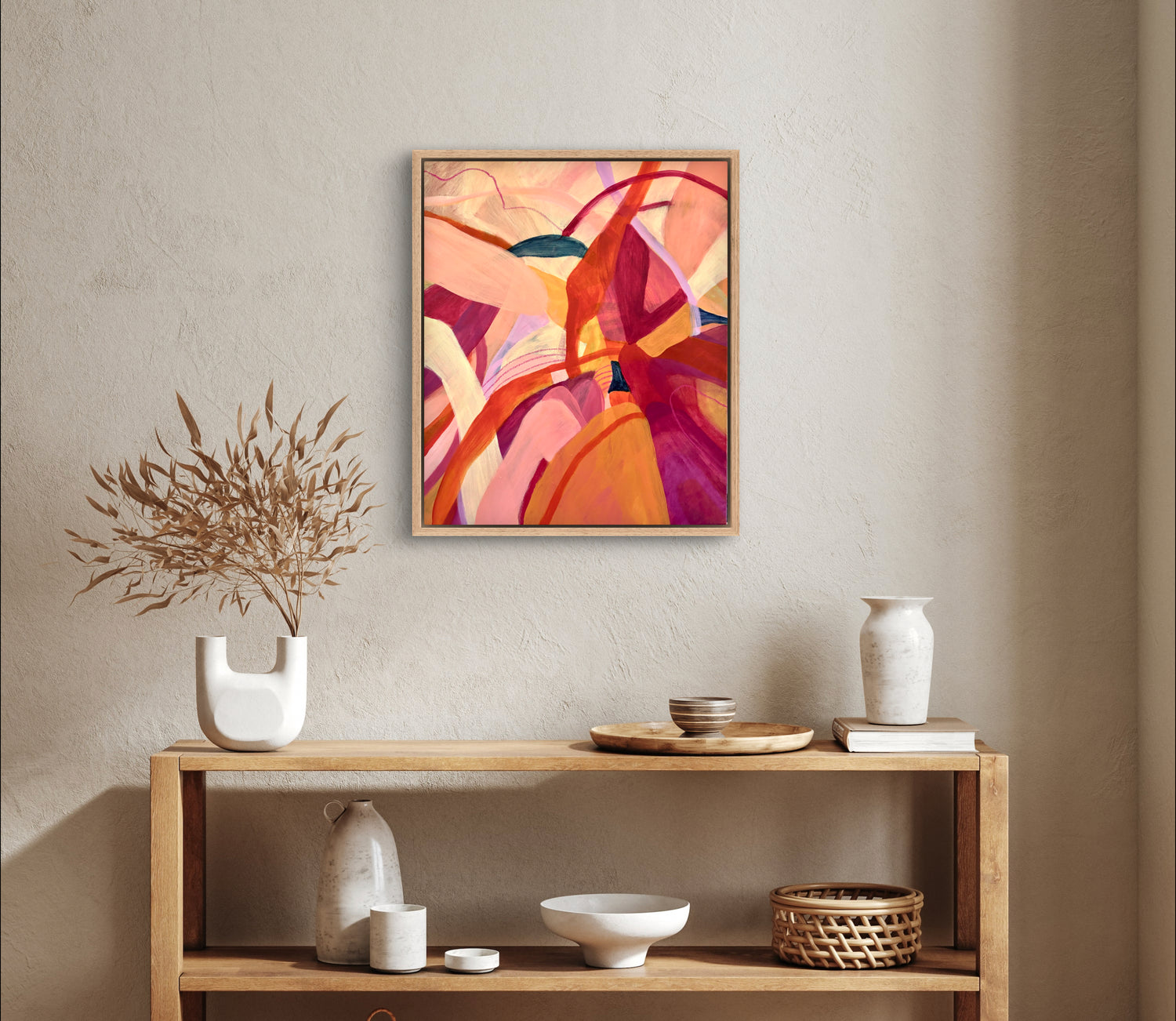 Framed Original painting of abstract botanical with bright pink, orange and yellow colours hanging above a console table with homeware objects