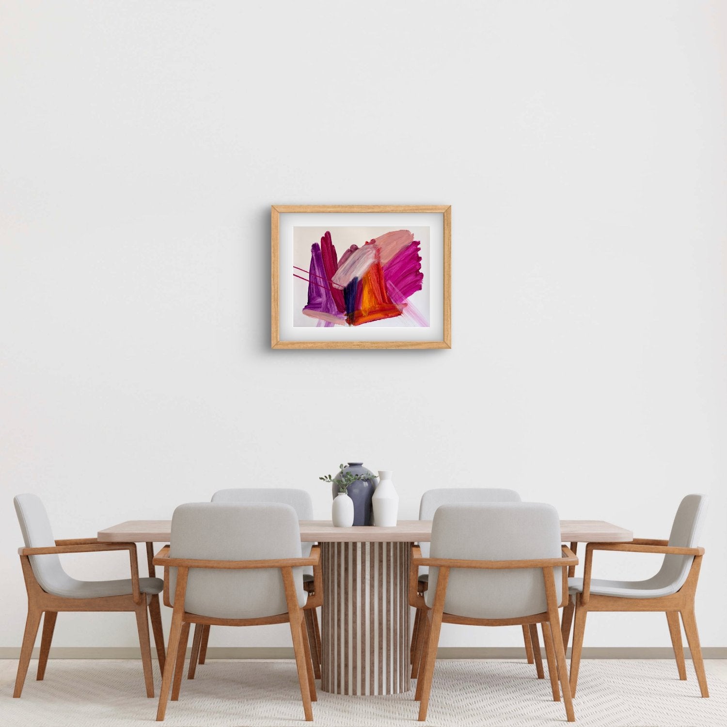 Bright expressive abstract artwprk on paper with pink, purple, orange and peach colours in an oak frame hanging above a dining table