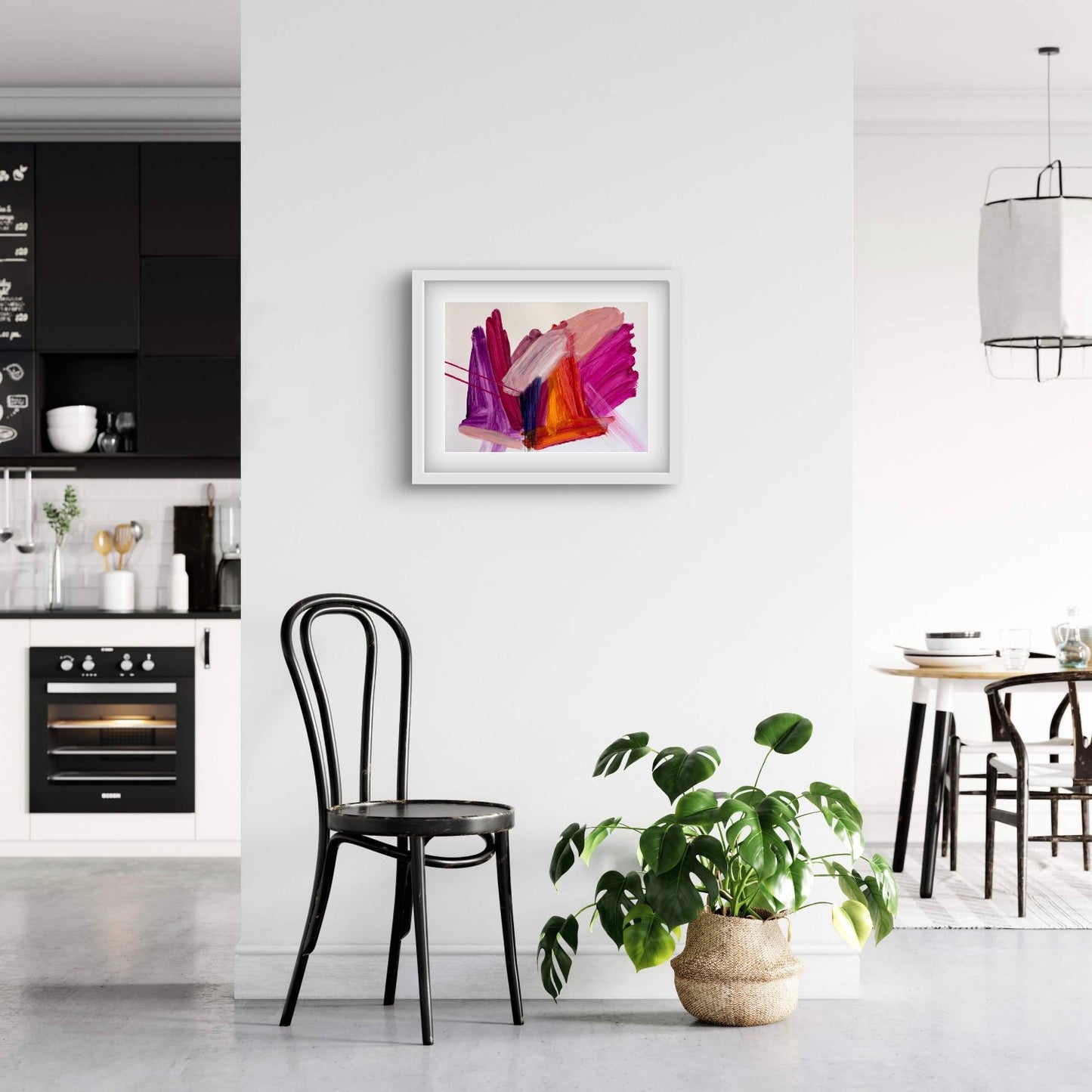 Bright expressive abstract artwork on paper with pink, purple, orange and peach colours in a white frame hanging in a white and black kitchen