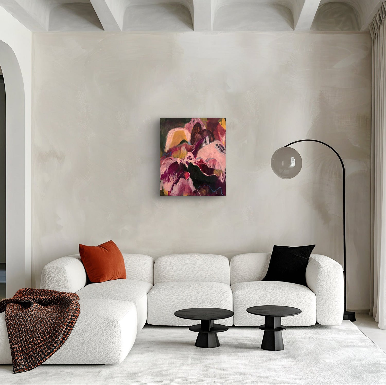 Modern living room with a white sofa, colorful painting, and decorative pillows.