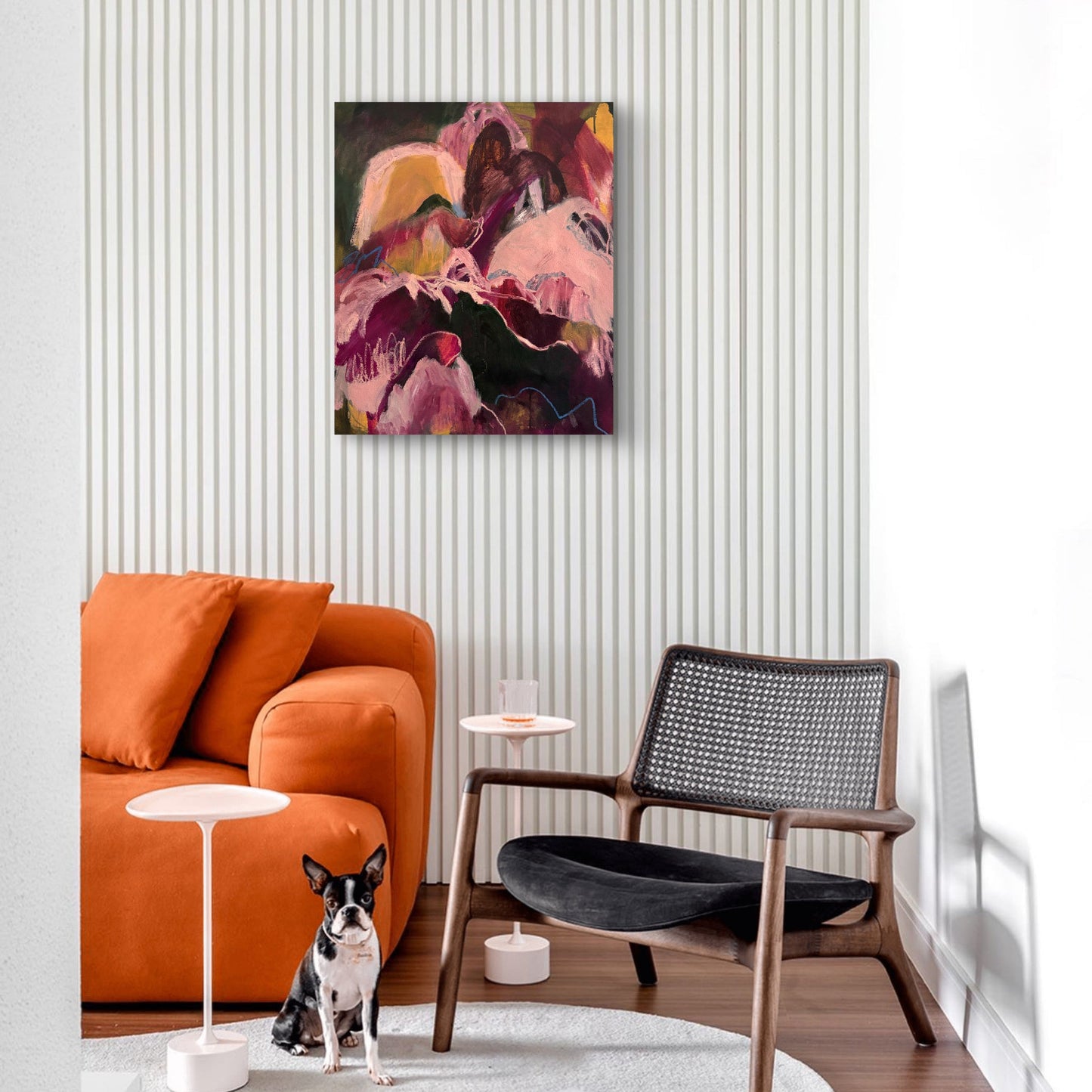 Modern living room with orange sofa, black chair, and abstract painting on white wall.