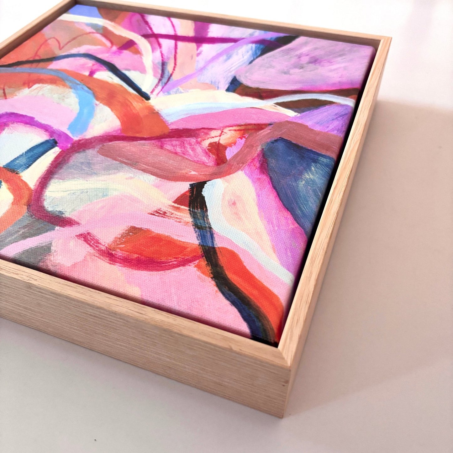 abstract acrylic painting with birght pink, orange and blue colours in an oak frame