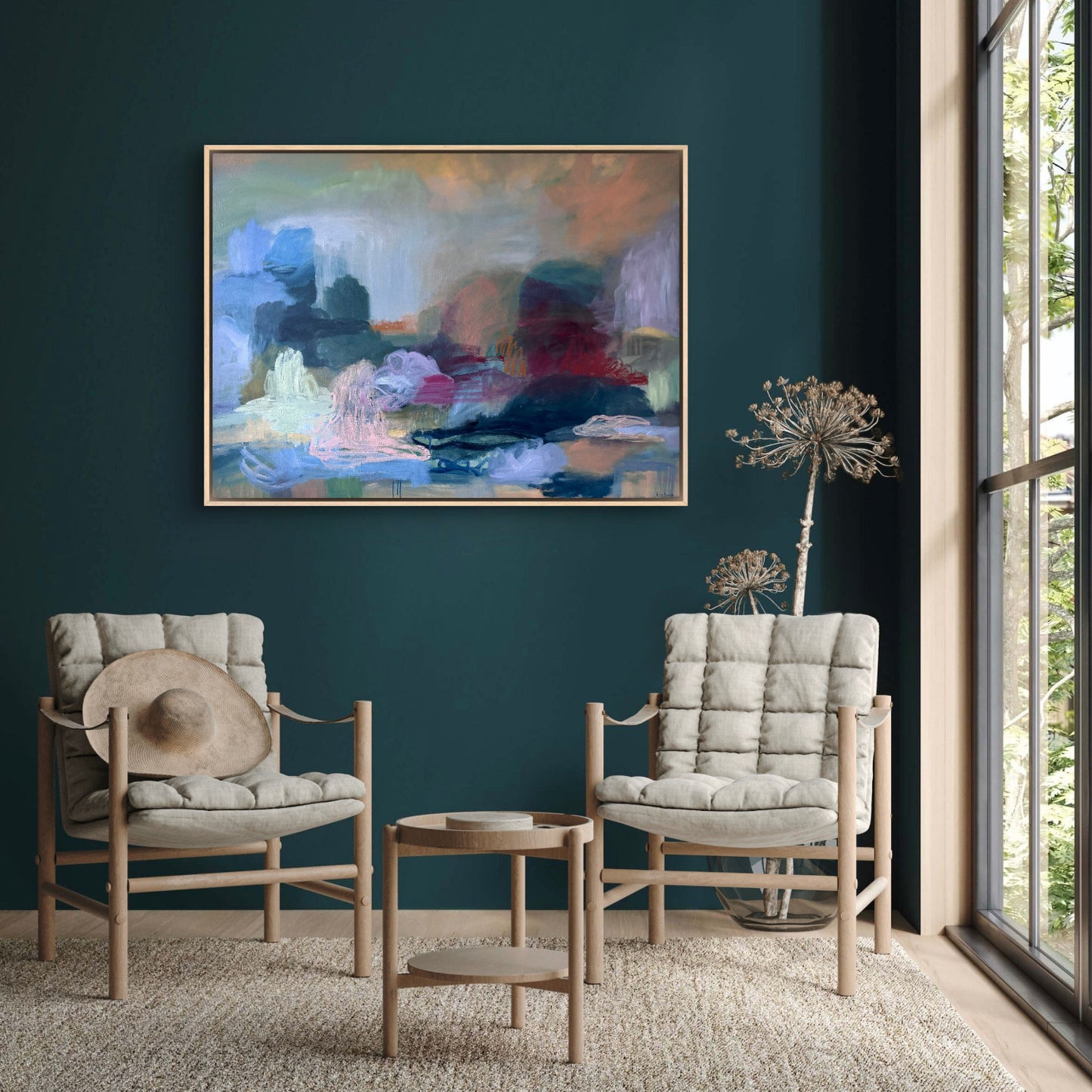 Two cushioned chairs with a small table against a dark blue wall with a colorful abstract painting.