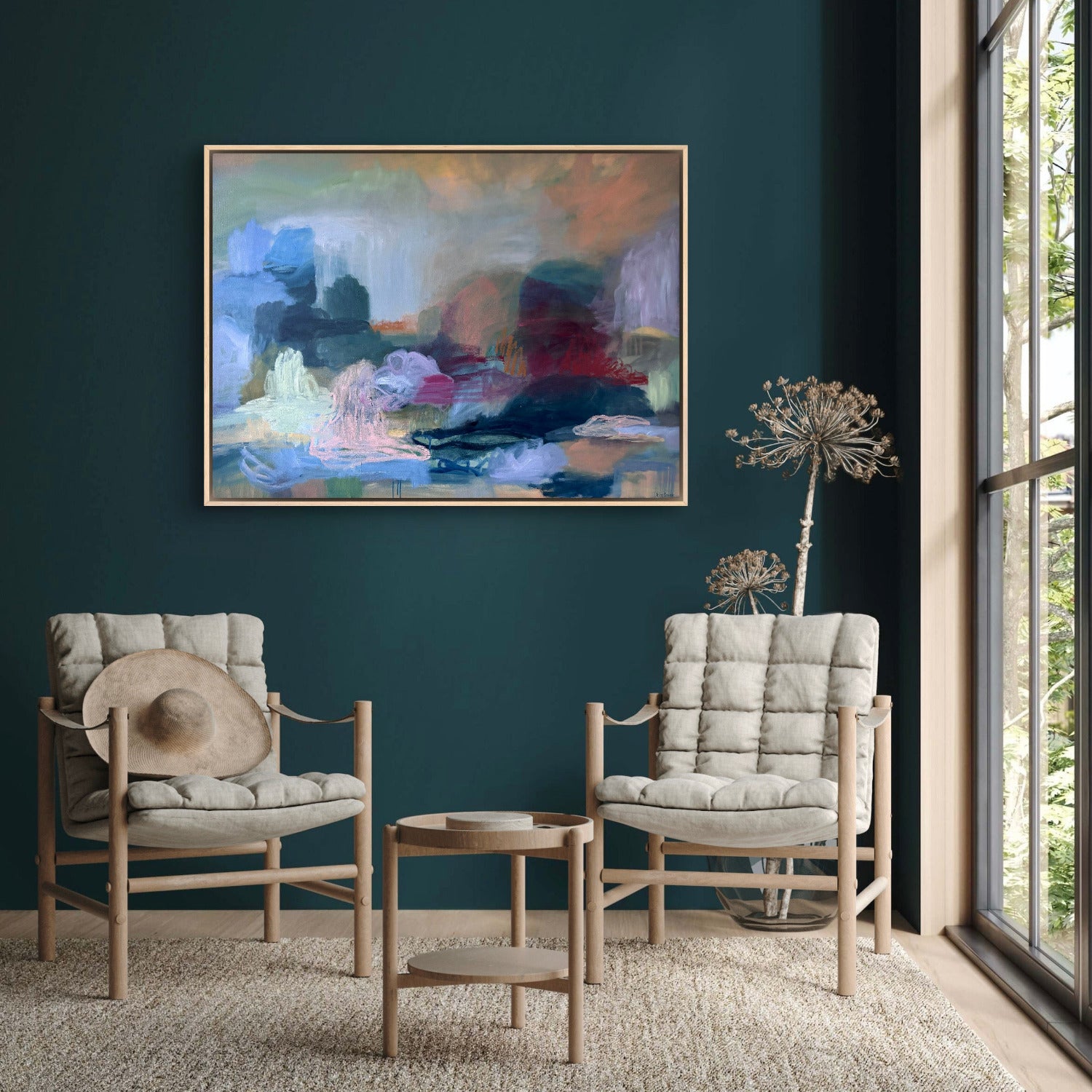 Two cushioned chairs with a small table against a dark blue wall with a colorful abstract painting.