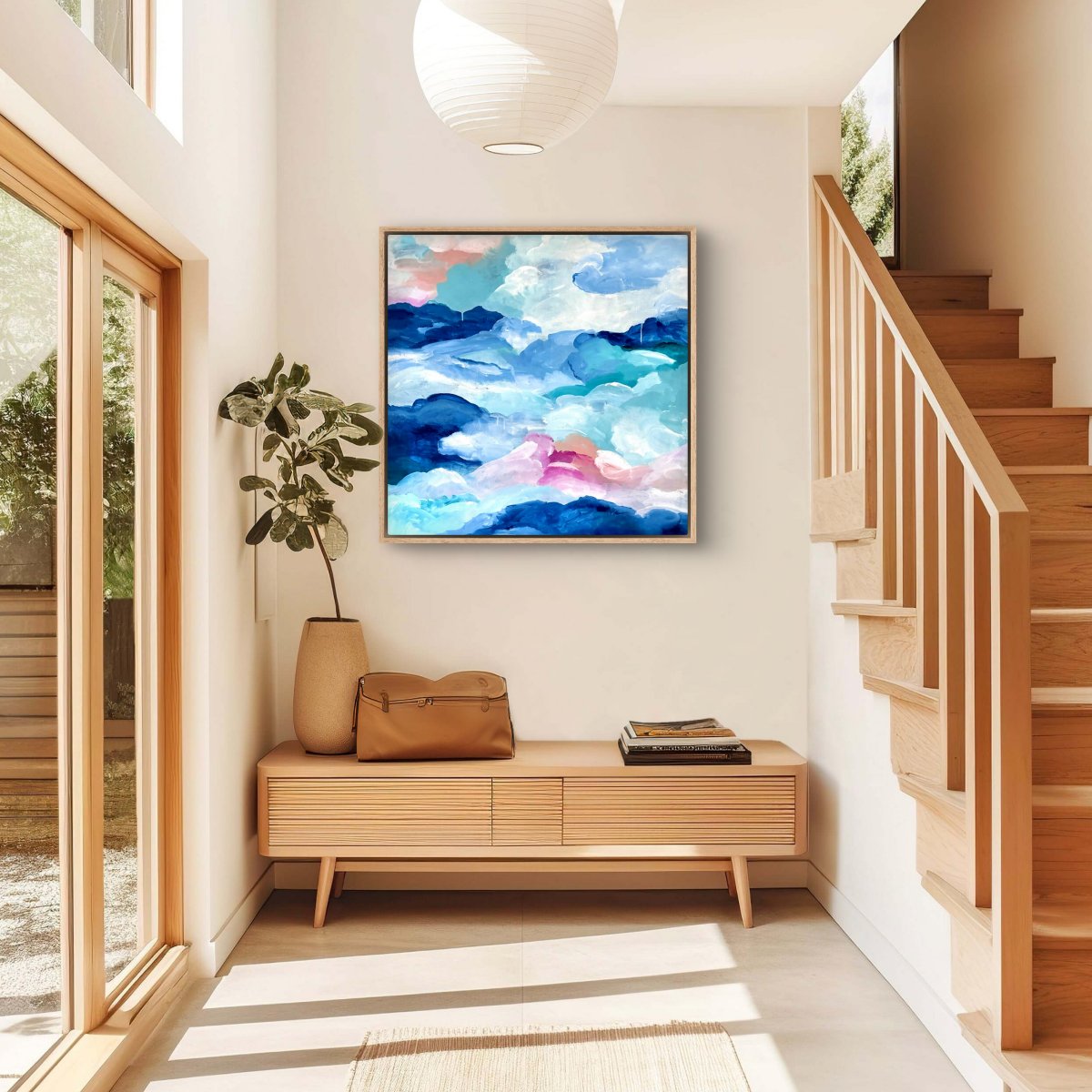 Framed original artwork of abstract clouds of blue, green, white and peach hanging in a hallway in a wooden themed house