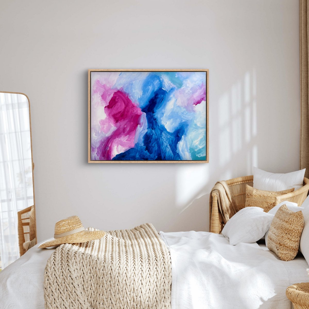 Framed original abstract painting with blue, pink and white colours hanging in a bedroom with a neutral palette