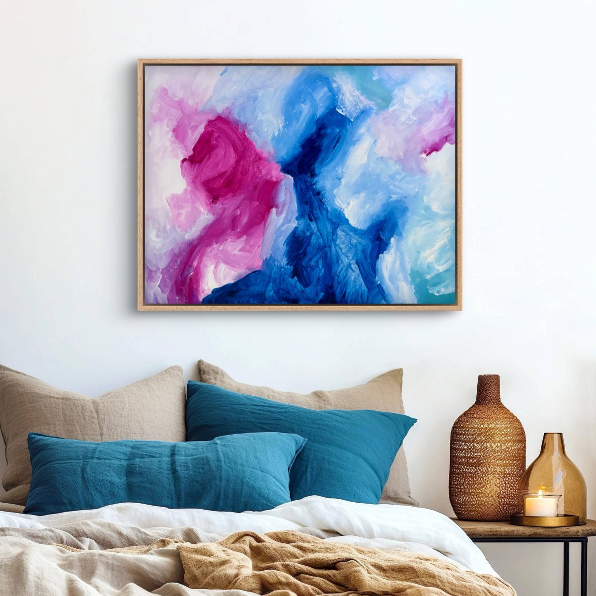Framed original abstract painting with blue, pink and white colours on a neutral background hanging above a bed with teal cushions