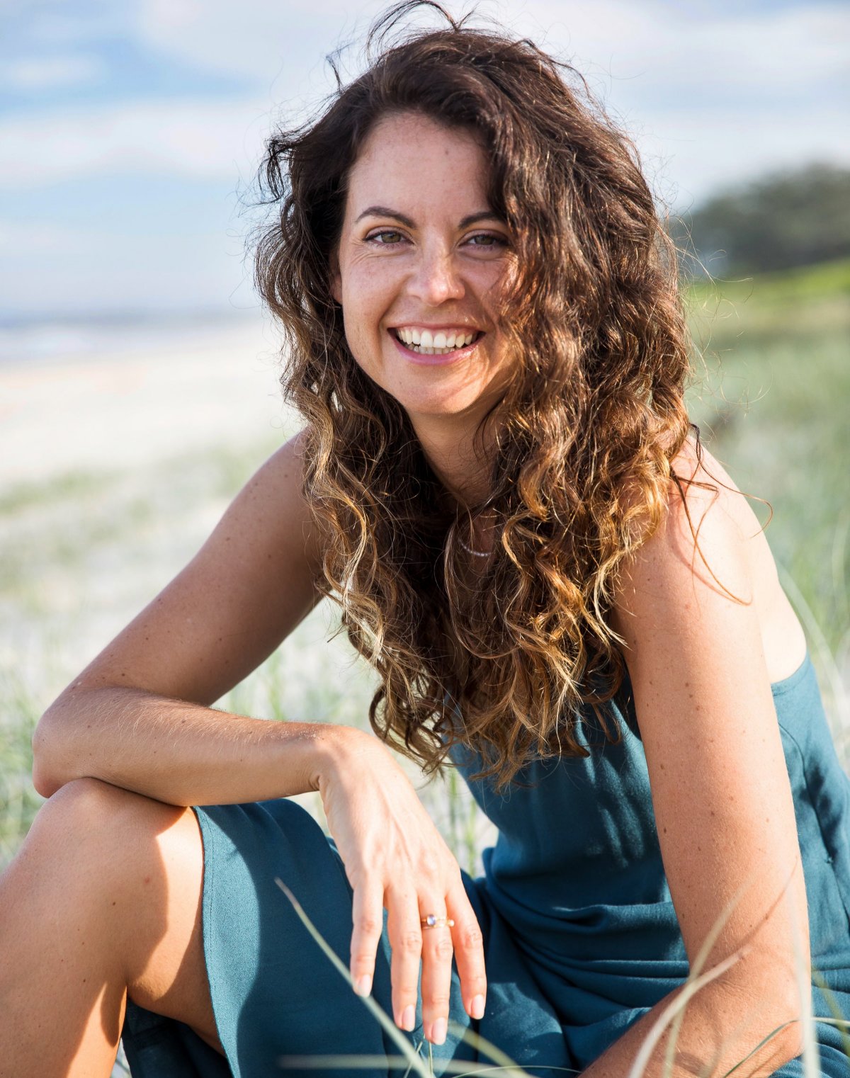 Image of Kim Stark smiling at the beach in a teal dress