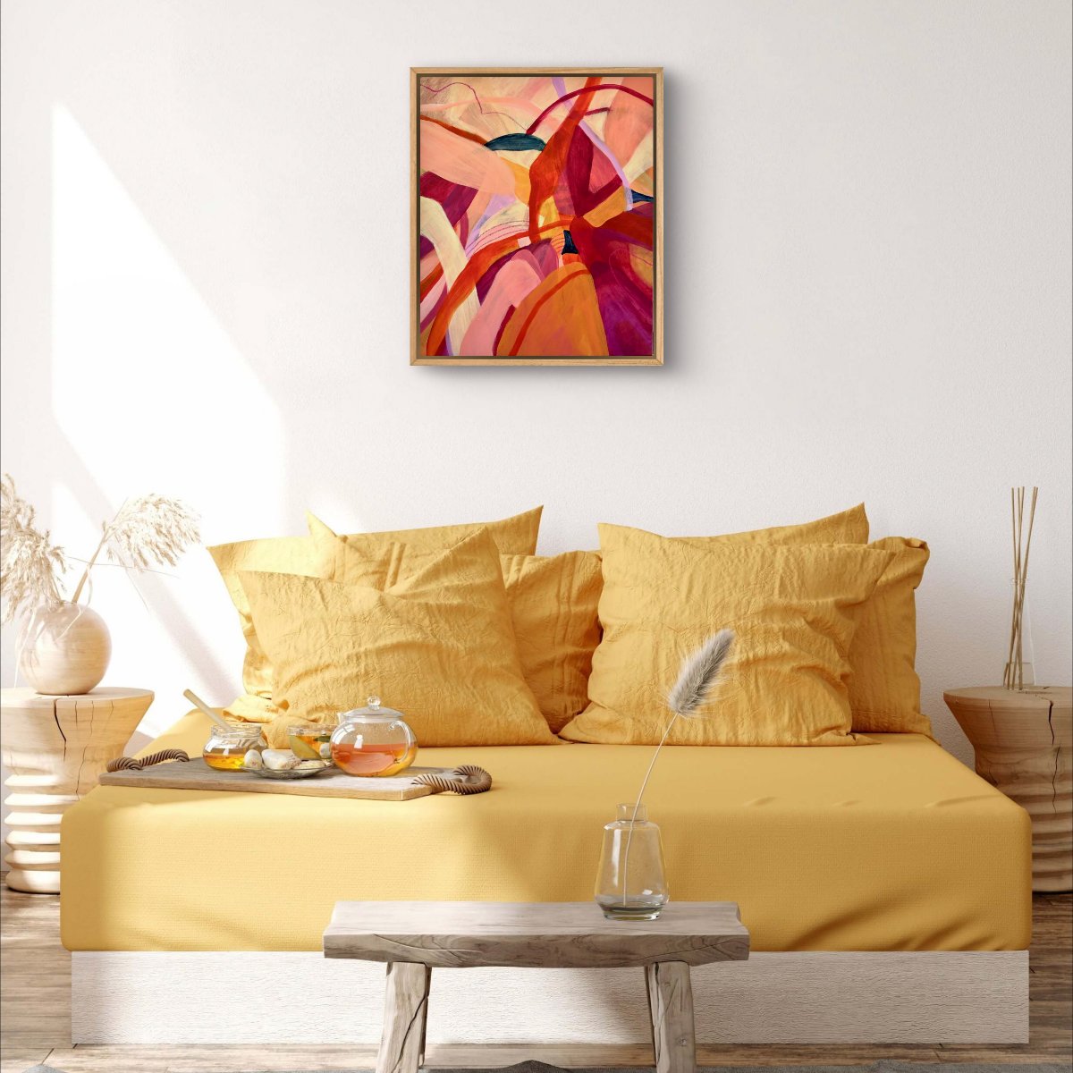 Framed Original painting of abstract botanical with bright pink, orange and yellow colours hanging above a yellow day bed