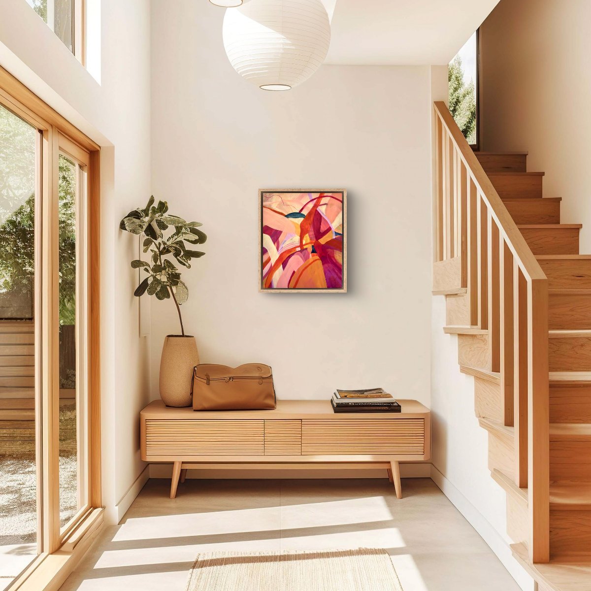 Framed Original painting of abstract botanical with bright pink, orange and yellow colours hanging in a well lit entrance with a wooden staircase