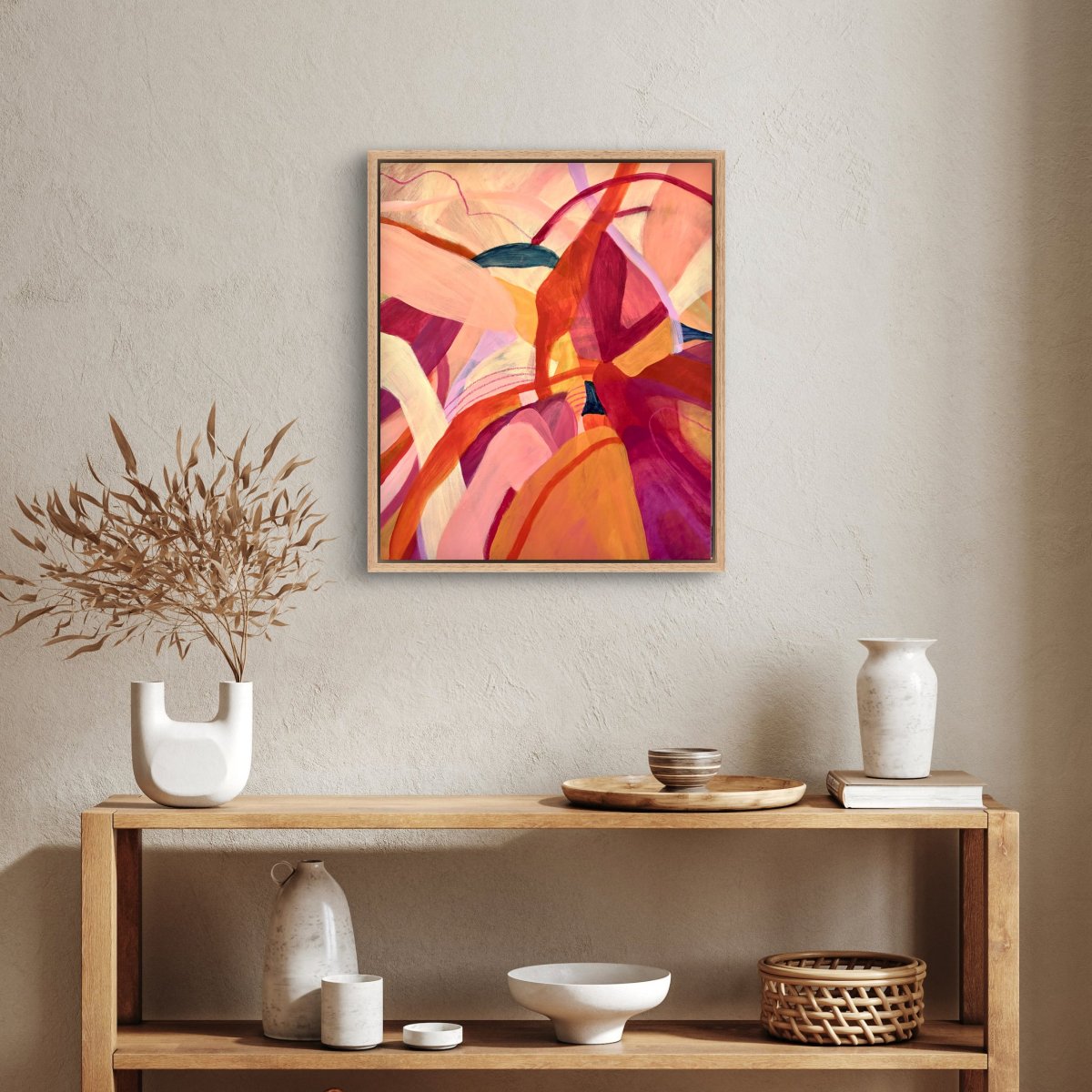 Framed Original painting of abstract botanical with bright pink, orange and yellow colours hanging above a console table with homeware objects