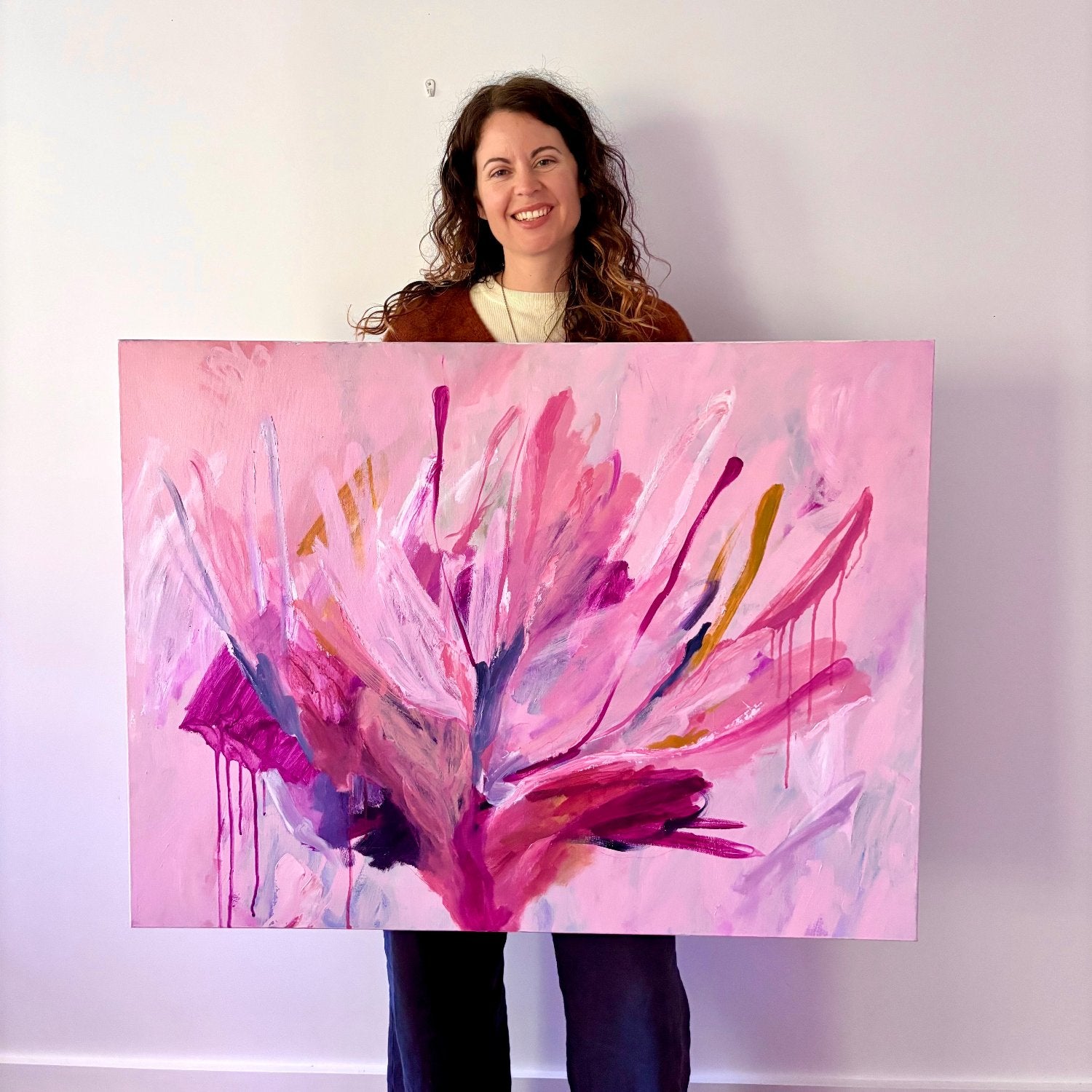 artist holds large botanical abstract acrylic painting with bright pink colours