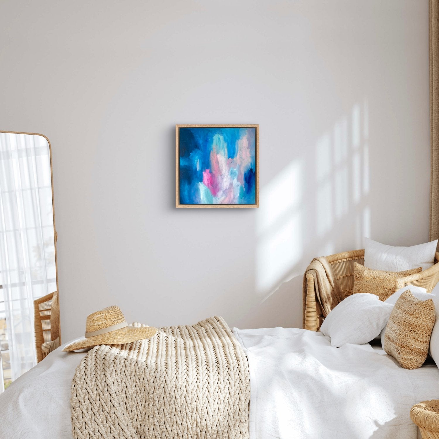 dark blue, peach and pink oil abstract painting  in an oak frame hanging in a white themed bedroom