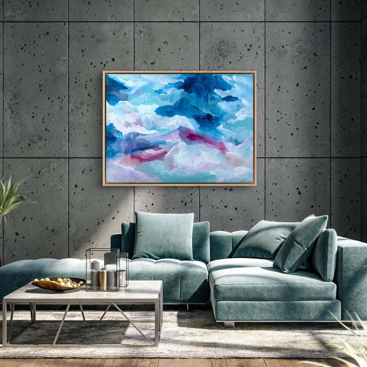 Original painting of abstract clouds in blue, white and pink hanging on a grey concrete wall in a loungeroom with a teal couch