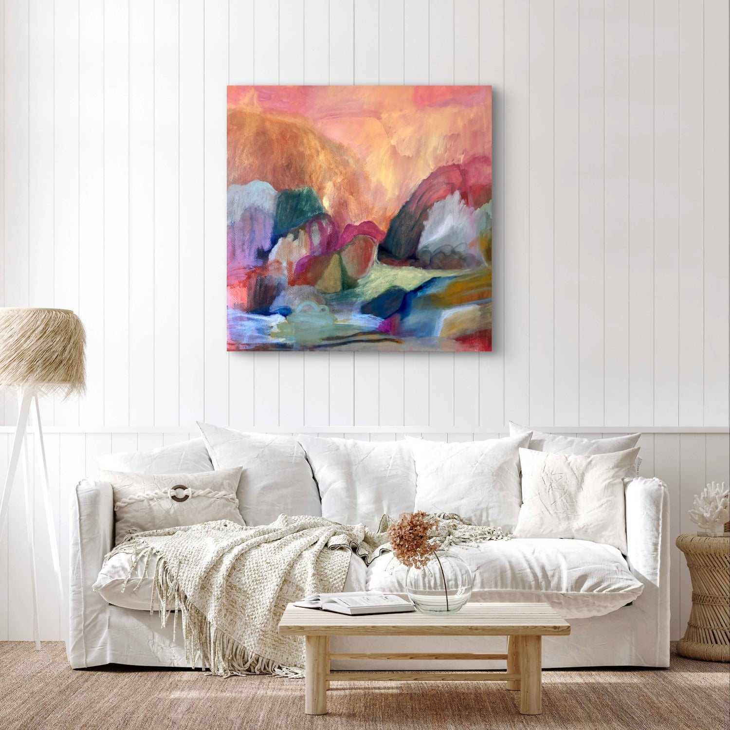Living room with a white sofa, coffee table, and colorful abstract painting on a white wall.