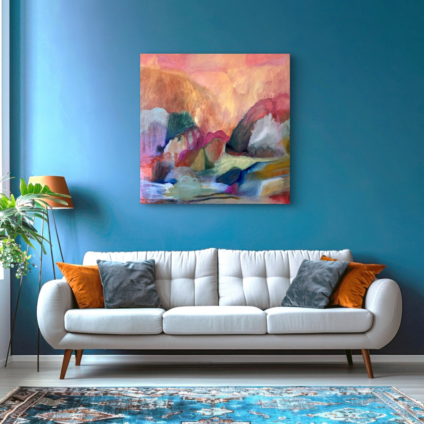 Living room with a white sofa, colorful pillows, and a abstract painting on a blue wall.