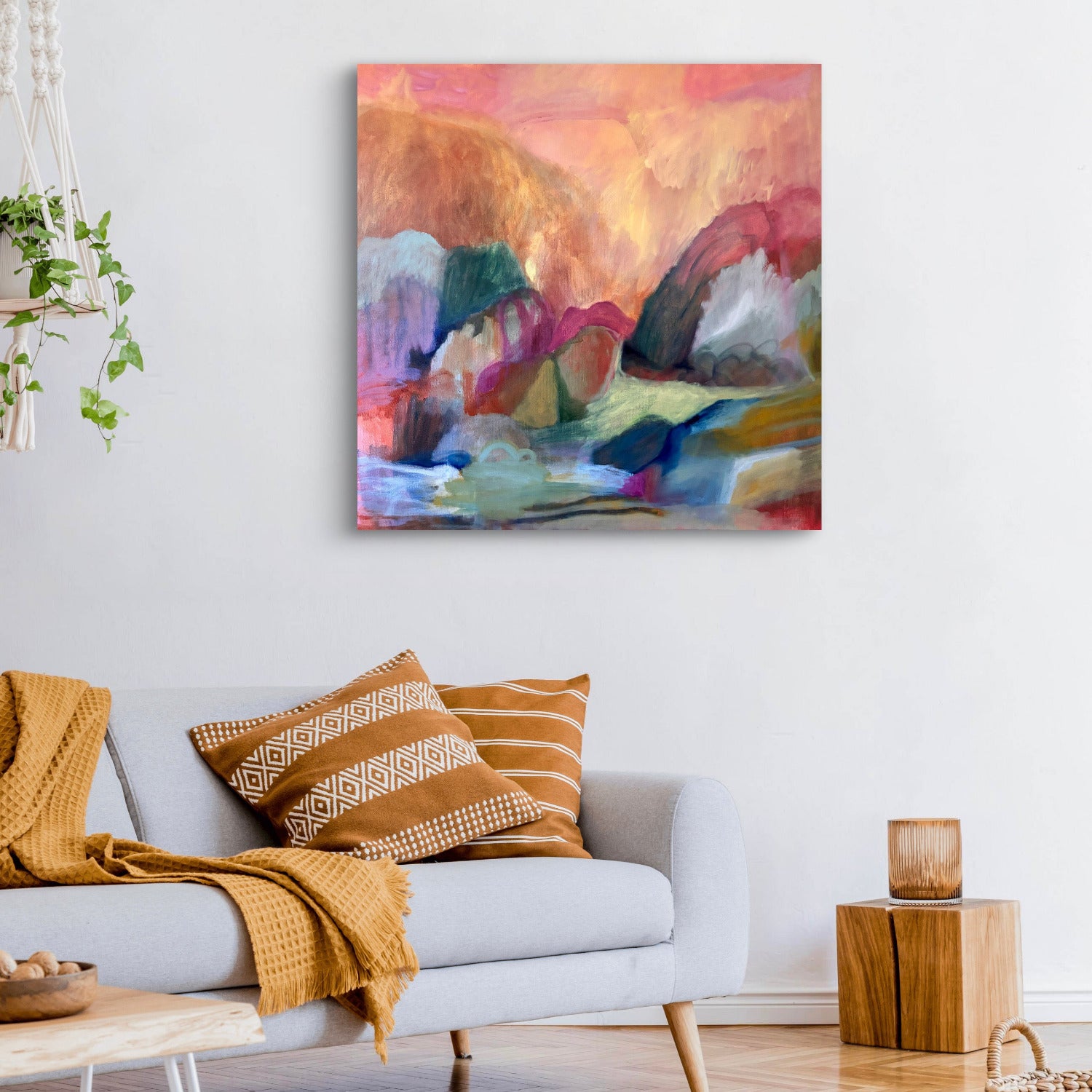 Living room with a colorful abstract painting on the wall, a gray sofa with patterned cushions, and a wooden side table.