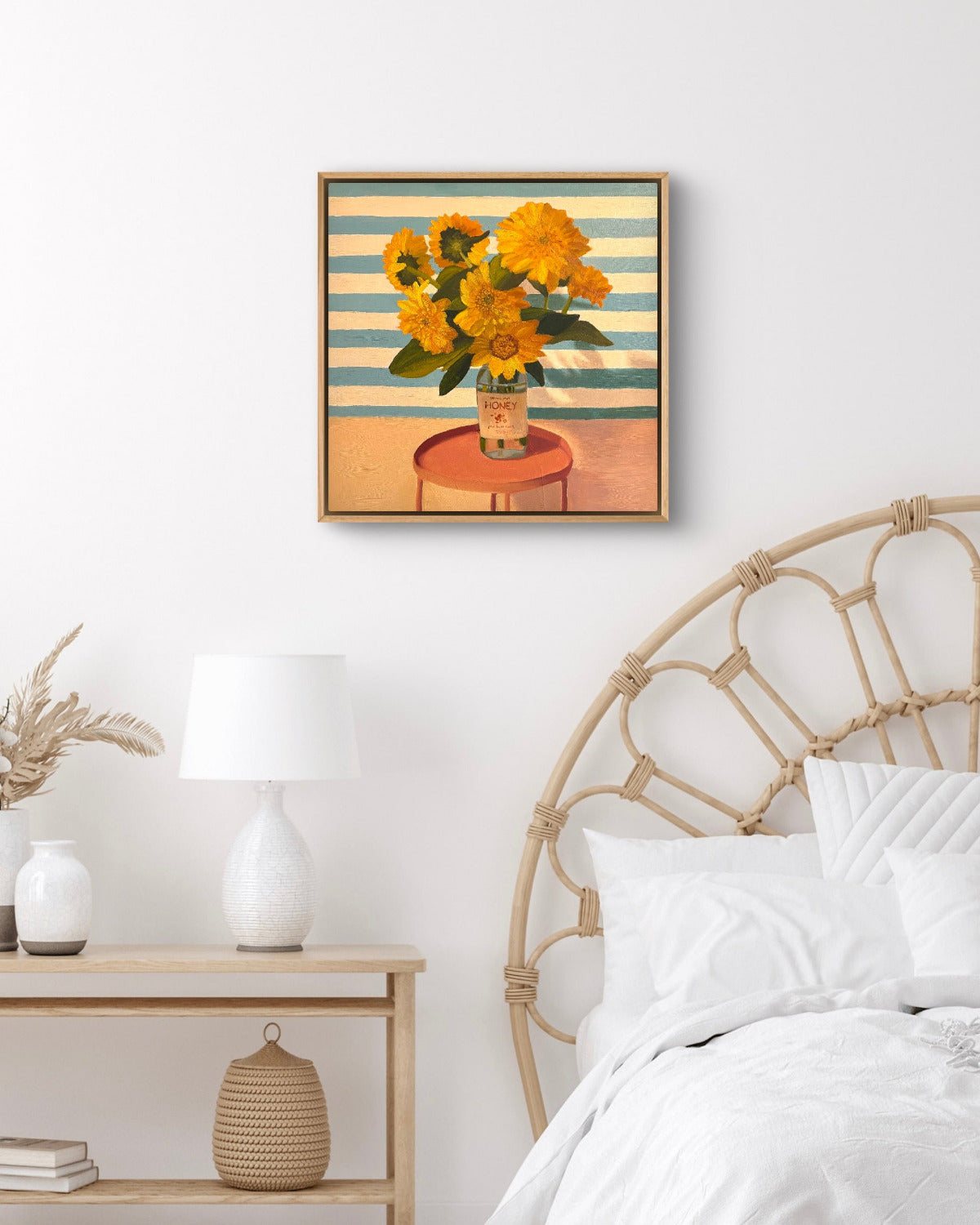 Framed artwork of sunflowers on a wall above a bed with a wicker headboard.