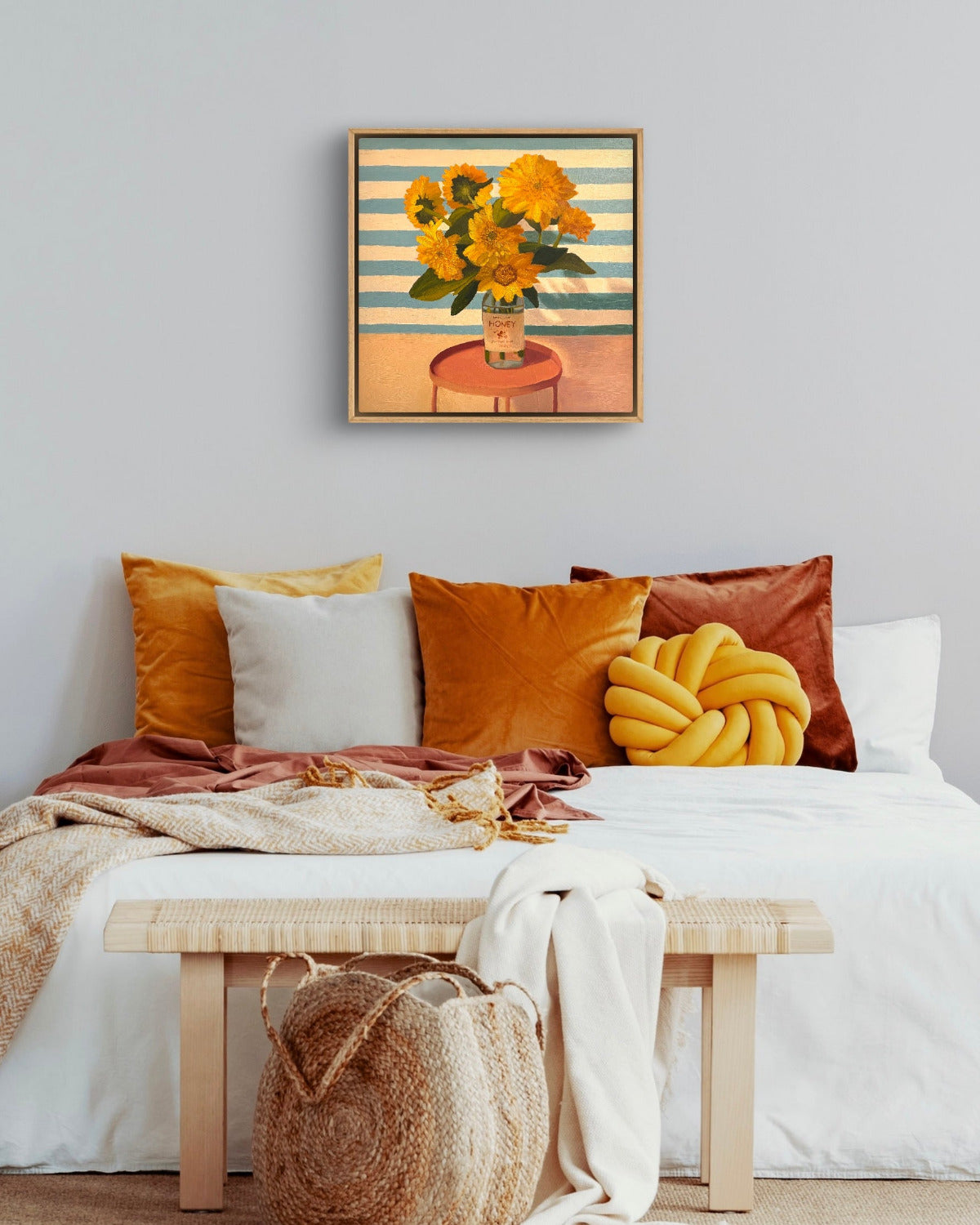Decorative bedroom with colorful pillows, a bench, and a floral painting on the wall.